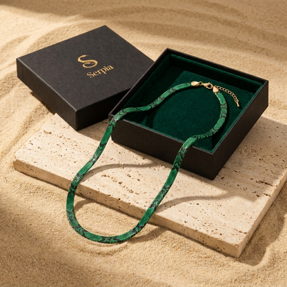 Confezione regalo Serpia aperta su travertino con la collana a serpente smeraldo