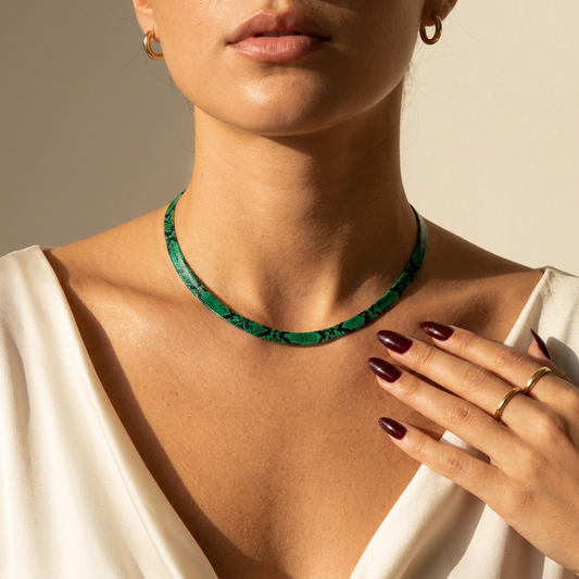 Donna che indossa la collana a serpente Serpia pitone smeraldo con la mano sulla clavicola